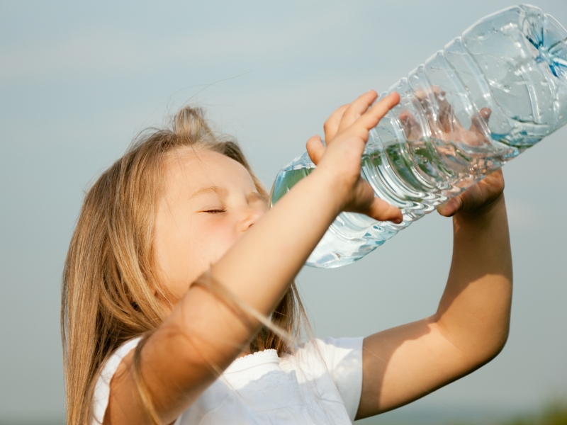 barn dricker vatten ut flaska